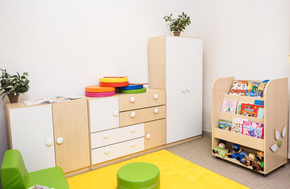 Moderní nábytek do dětského pokoje - úložné skříňky, knihovna s knihami a hrací koutek v příjemném designu.