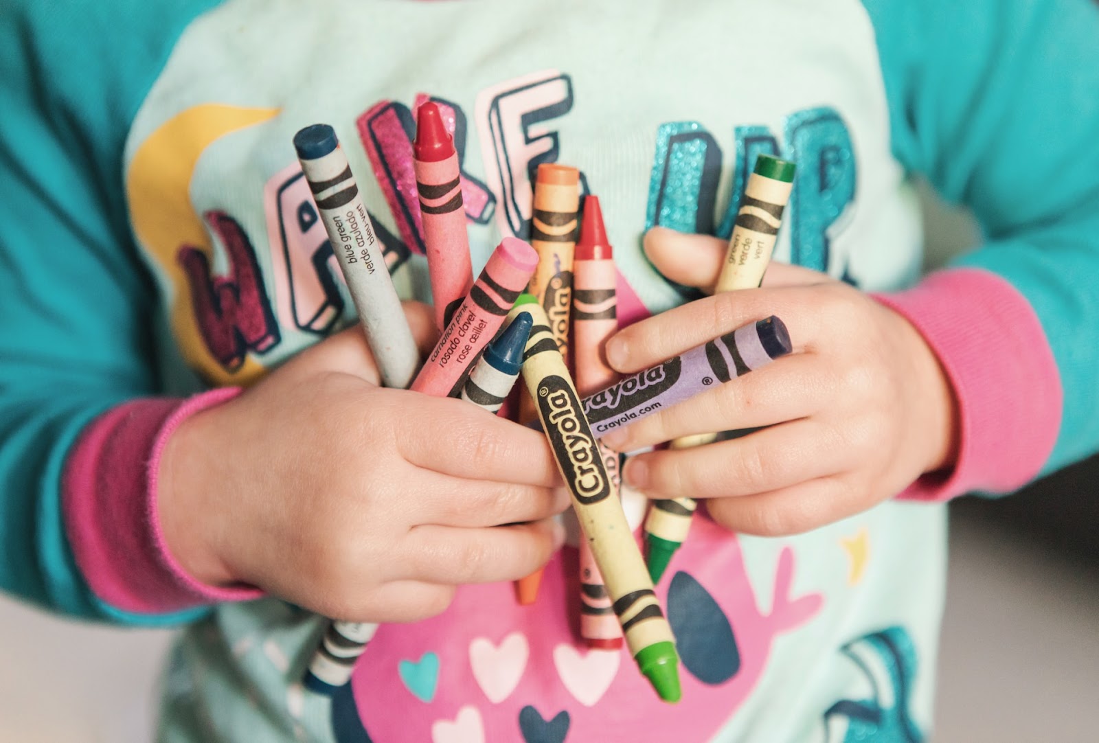 Dieťa drží farebné voskovky Crayola pripravené na kreatívnu výtvarnú aktivitu.