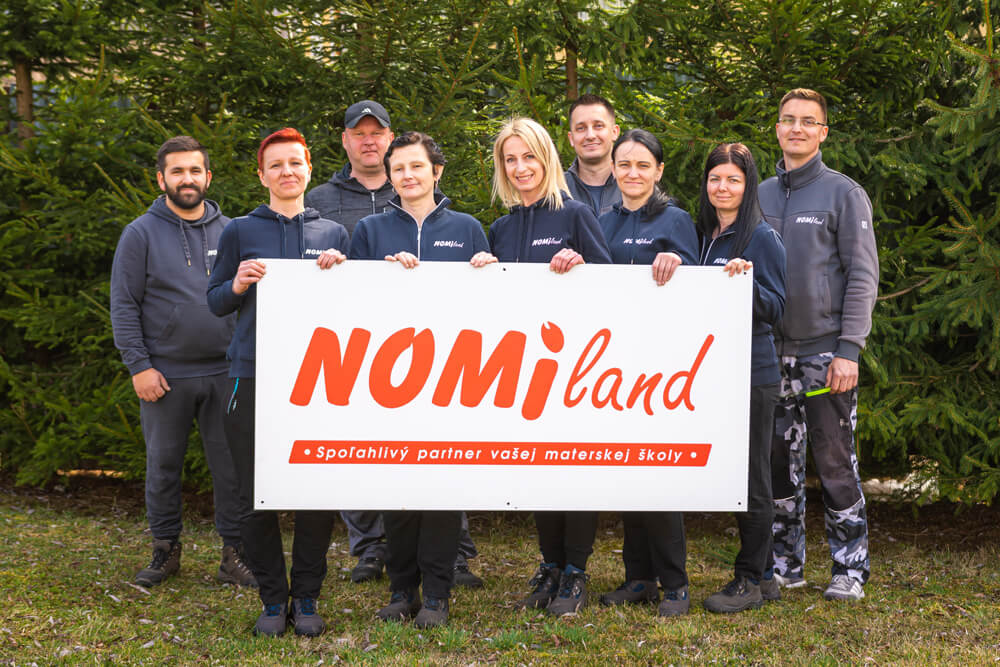 Tím spoločnosti Nomiland s informačnou tabuľou pred sídlom firmy, spoľahlivý partner materských škôl.