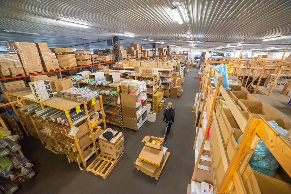 Rozsáhlý sklad společnosti Nomiland s regály plnými edukačních pomůcek a školního vybavení.